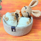 Handmade crochet bunny in a basket on a wooden surface