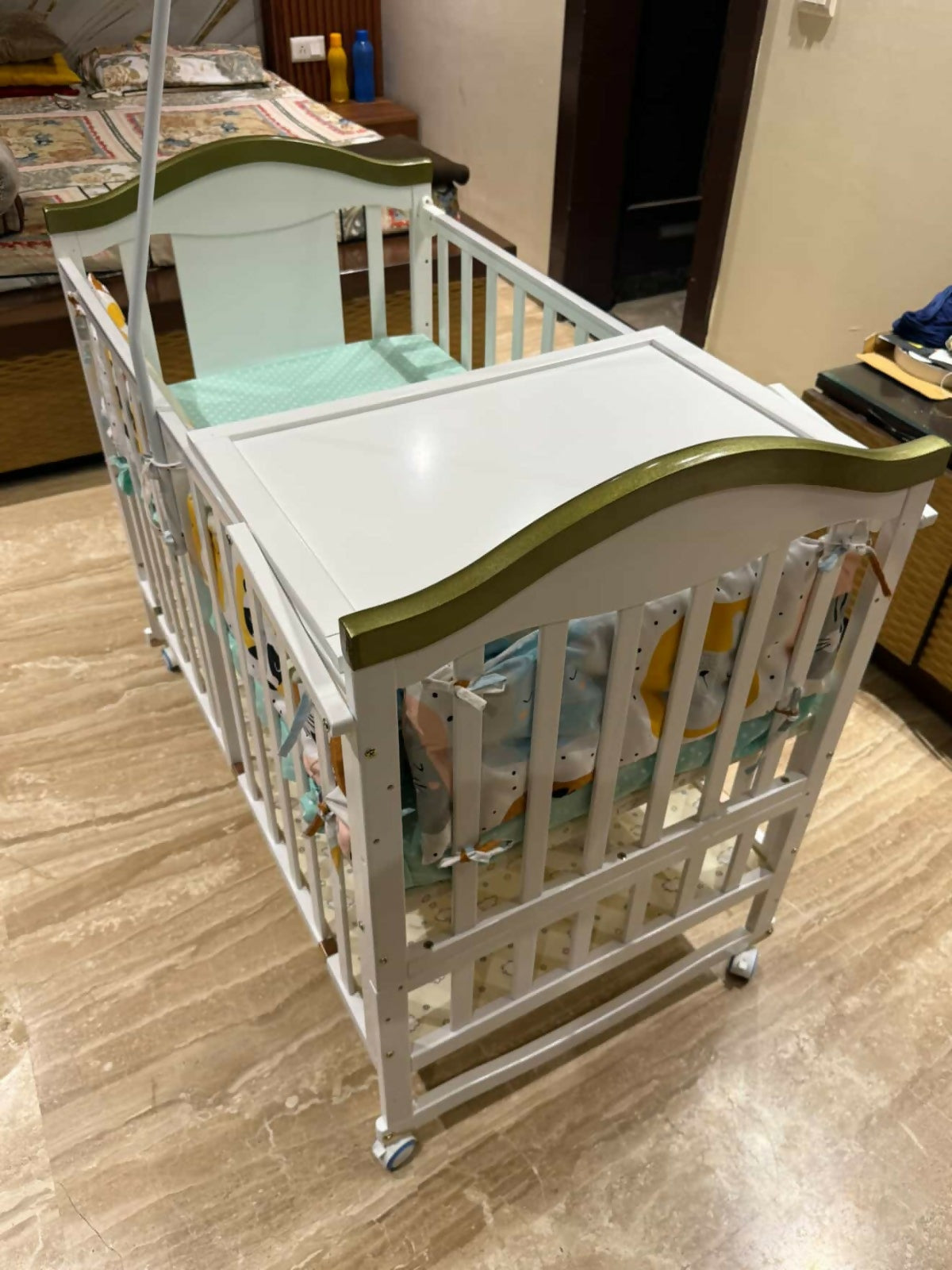 White crib with green accents on a tiled floor