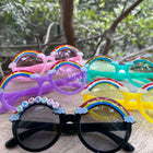 Colorful sunglasses with rainbow frames on a wooden surface with a natural background