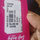 Close-up of a product label with text and a barcode on a pink background.