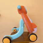 Children's multicolored scooter on a wooden surface with a beige wall background