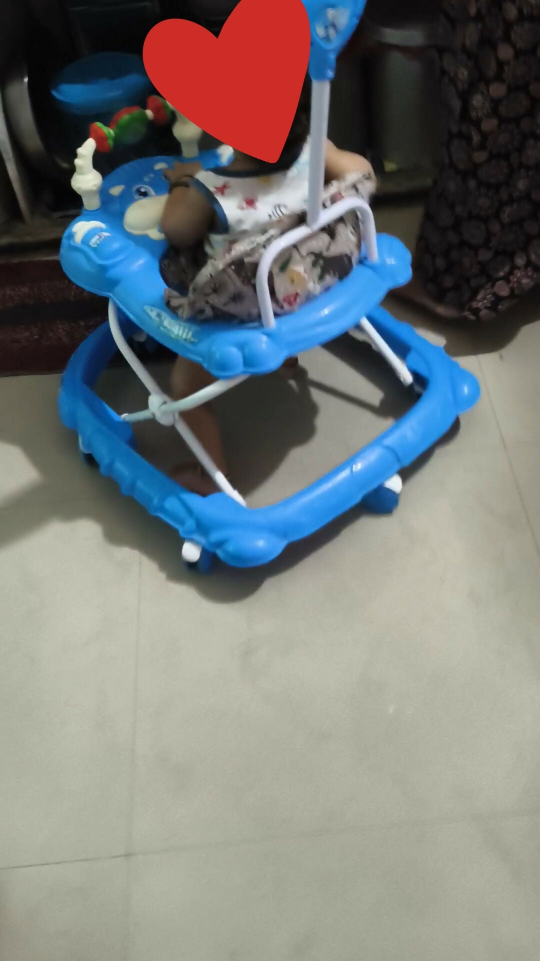 Blue baby walker on a tiled floor with a heart overlay
