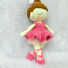 Crocheted doll with a pink dress and brown hat on a white background