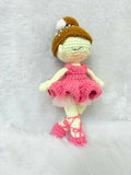 Crocheted doll with a pink dress and brown hat on a white background