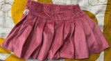Pink skirt with white polka dots on a yellow and white patterned background