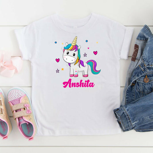 White t-shirt with a unicorn graphic and 'Anshita' text, paired with shoes and denim jacket on a white surface.