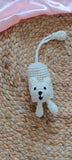 White crocheted mouse toy on a woven surface