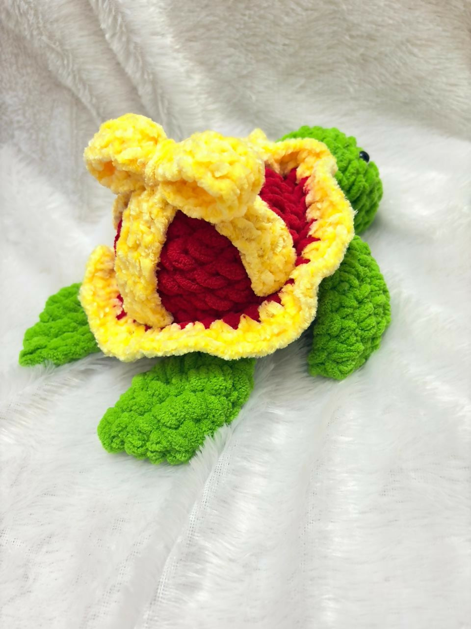 Crocheted turtle toy with a yellow shell and green body on a white background