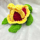Crocheted turtle toy with a yellow shell and green body on a white background