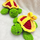 Two green crochet turtles with yellow and red shells on a white background