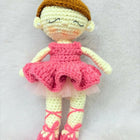 Crocheted doll in a pink dress and brown hat on a white background