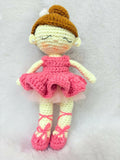 Crocheted doll in a pink dress and brown hat on a white background