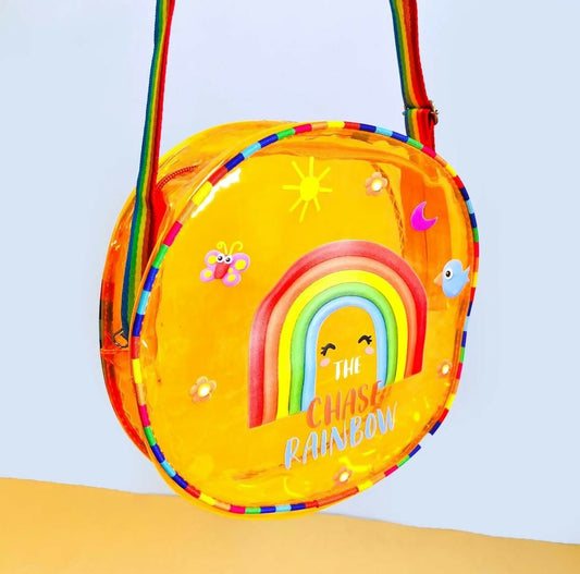 Yellow crossbody bag with rainbow design and text on a light blue background